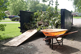 Open Dumpster With Ramp and Wheelbarrow Loaded With Yard Waste