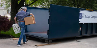 Man Carrying Household Junk Into a Dumpster