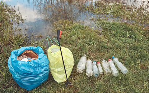 Materials collected at a river cleanup being sorted into piles by trash type.