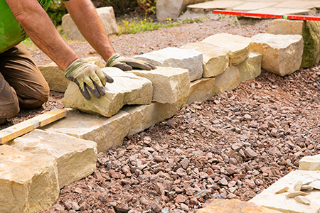 Person Laying Down Stone for a Wall