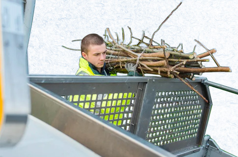 Worker Loading Stack of Branches Into Truck